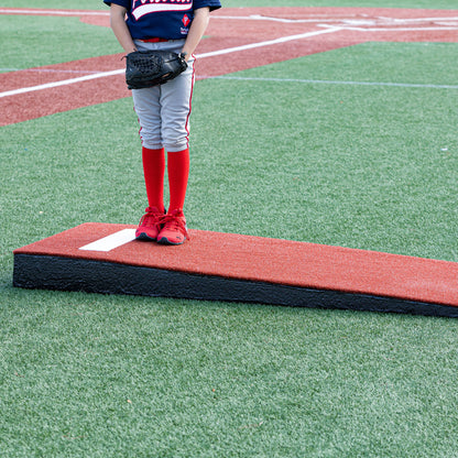 Pitcher practicing on a red junior pitching mound